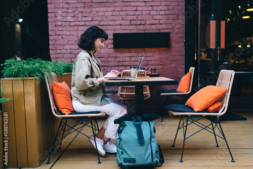 Concentrated woman sitting in cafe with laptop and smartphone