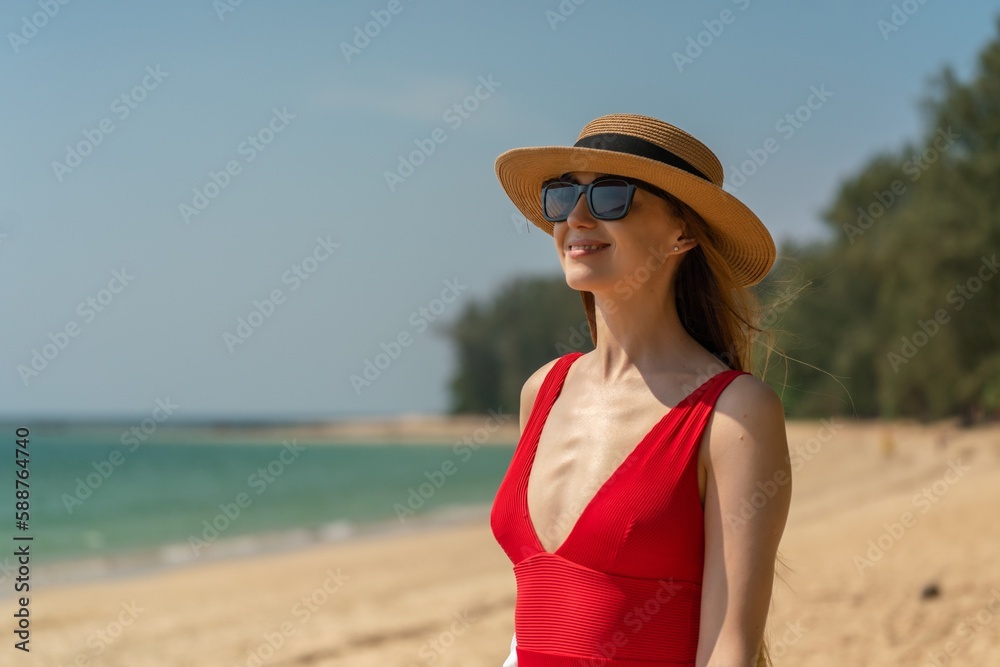 Beautiful caucasian female sexy woman lady in red swimsuit bikini on the beach with black sunglasses enjoying the sun tan and sea breeze happily. Happy holiday!