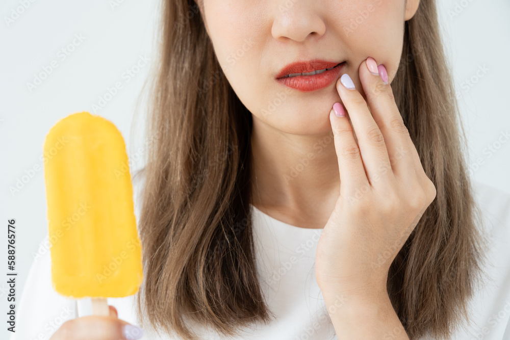 Asian woman feel sensitive teeth after eating ice cream, female suffer