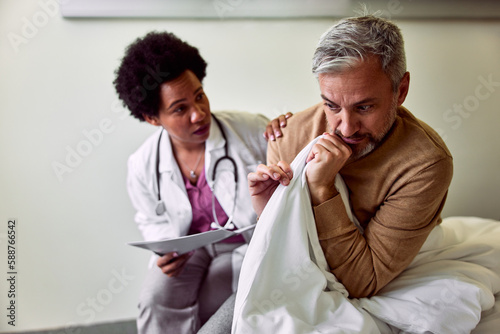 Fotografie A female African-American psychiatrist sitting with a frightened male patient with psychological problems