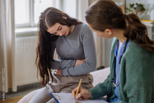 Foto Teenage girl having stomach ache, young doctor examining her.