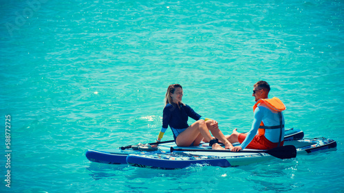 Man and woman sitting on a stand up paddle boards. Couple taking time together relaxing on sup boards © Philipp Berezhnoy