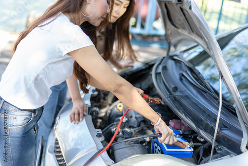 Two Asian people try to check the car engine and wait for assistance after a car breakdown on street. Concept of a vehicle engine problem or accident and emergency help from a Professional mechanic © Prot