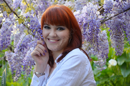 portrait of a smiling young woman in a garden with blooming wisteria