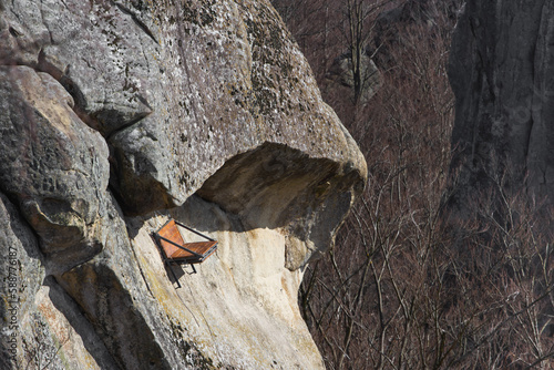 A bench nailed to a sheer cliff high in the mountains for the rest of rock climbers. photo