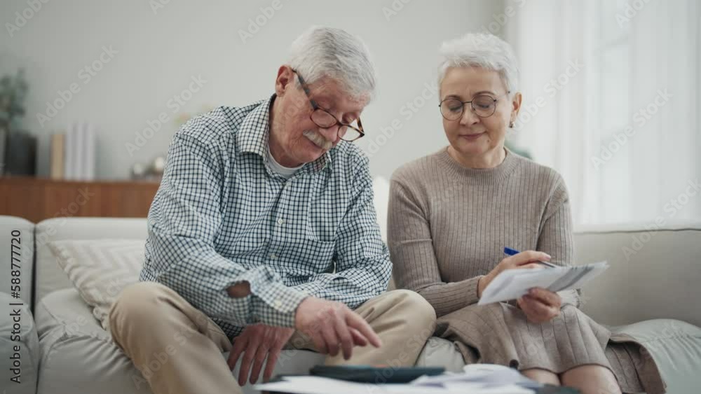 Worried senior retired couple checking calculating bills sitting on couch at home. Do paperwork discuss unpaid debt taxes, stressed family. Financial difficulties, money problem in elderly age concept Worried senior retired couple checking calculating bills sitting on couch at home. Do paperwork discuss unpaid debt taxes, stressed family. Financial difficulties, money problem in elderly age concept