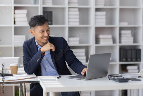 Handsome young business asian man using digital laptop at Busy elegant bearded adult company director, checking the company finances, at the office. © David