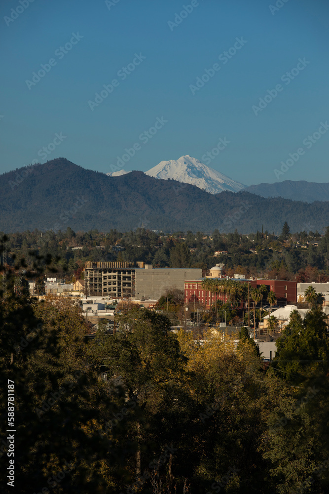 Afternoon snow covered view of the peak of Mount Shasta and the downtown skyline of Redding, California, USA.