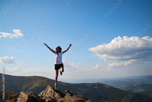 Young women standing on rock on top of the mountain. Feeling happy and free. Natural landscape in summer. Sunny rural scenery. Nature protection concept. Breathtaking mountain view.On top of the world