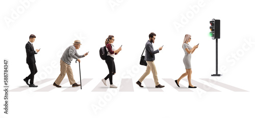 Full length profile shot of people crossing street at a pedestrian crossing and using mobile phones