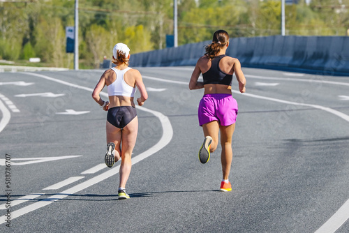 back two female runners running on overpass marathon race, endurance sports competition, woman jogger athlete