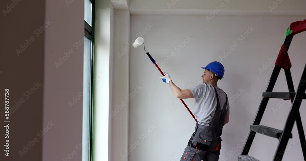 Painter builder with roller paints walls indoors. Instructions for correct painting of walls Painter builder with roller paints walls indoors. Instructions for correct painting of walls