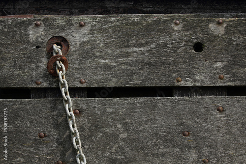 A close-up of a chain attached to a wooden fence 