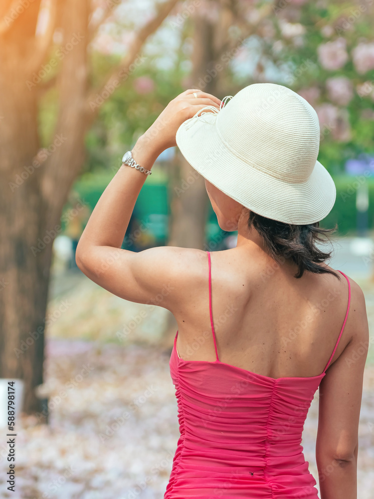 Back view of woman in pink dress wears straw hat and posing to take a ...