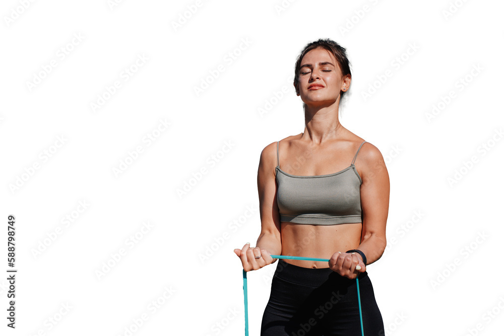 Tanned caucasian young fit hispanic woman in sportswear trains with rubber expander against transparent background, sunny summer day. Italian girl at workout makes exercise eyes closed. 