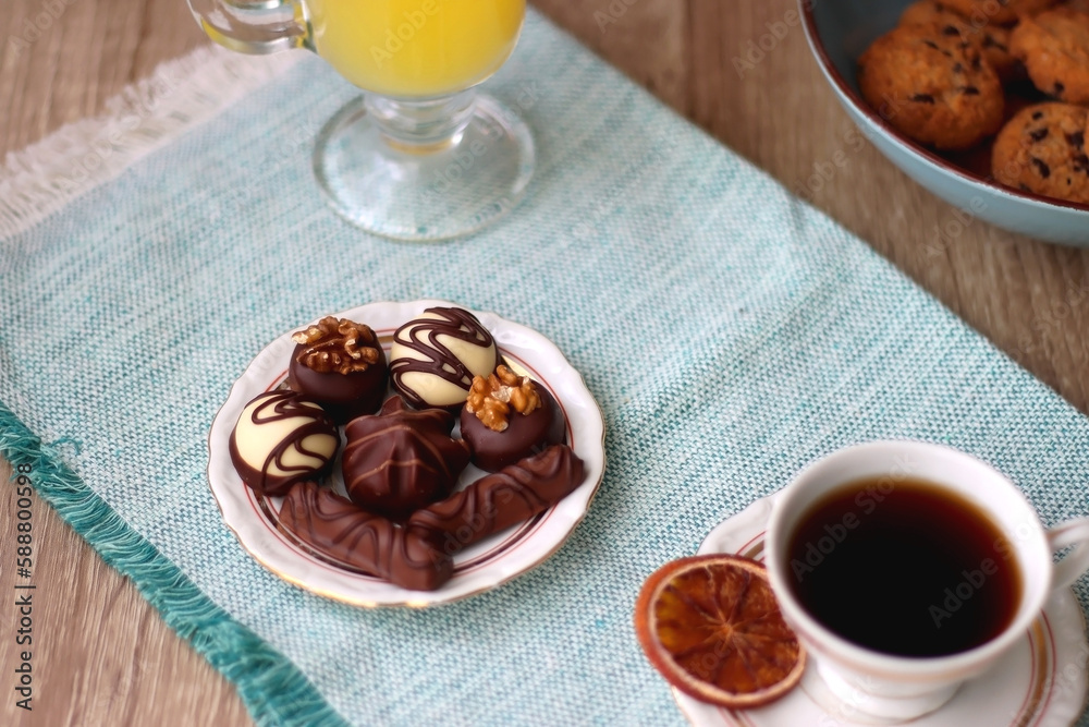 Φωτογραφία Plate of chocolate pralines, bowl of cookies, cups of tea, glasses of juice and lit candles on the table
