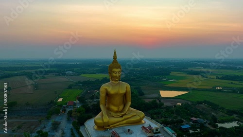 scenery sunset behind the great golden Buddha landmark of Thailand at wat Muang Ang Thong Thailand. .The largest Buddha statue in the world Surrounded by rice fields..colorful sky background.
