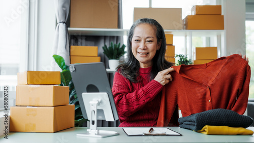 Successful asia people woman entrepreneur with parcel boxes clothing online store checking email order in tablet and laptop at sofa home office SMEs small company. © M+Isolation+Photo