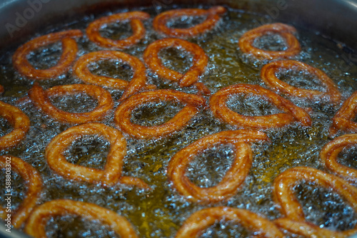 Turkish Dessert Churros Halka Tatli frying in hot oil. Turkish doughnuts or traditional ring sweet, yağda kızarmış halka tatlısı                 photo