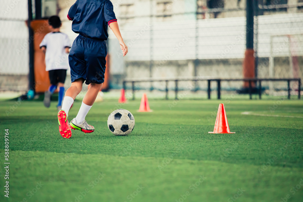 Children playing control soccer ball tactics cone on a grass field with for training background