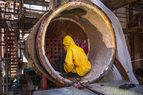 Male workers use high-pressure water jets to clean splashing the dirt of tube boilers in industrial areas or toxic hazardous material sulfur