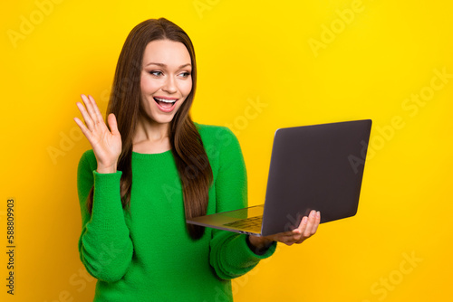 Portrait of cheerful nice person use netbook arm waving hi video call isolated on yellow color background