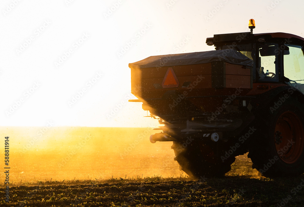 Fototapeta premium Tractor spreading artificial fertilizers in field