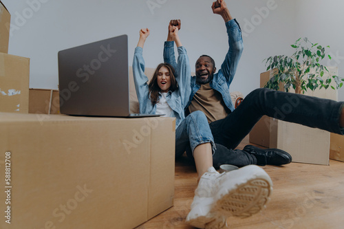 couple using laptop in their new house on moving day. a couple reacts emotionally to watching a video from a laptop