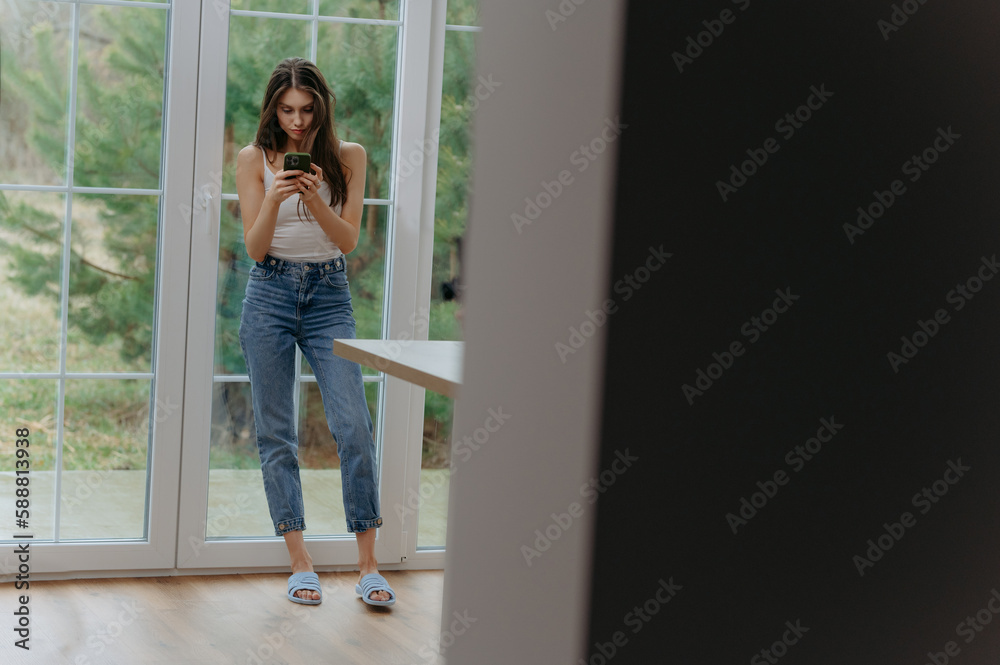 girl browsing the Internet on her cell phone, chatting, reading text messages, using virtual applications at home