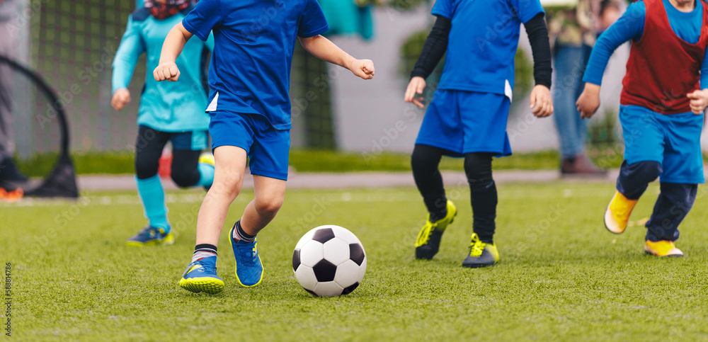 Kindergarten children playing a soccer game at the football pitch. Group of little kids running and kicking football ball