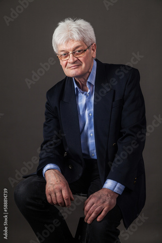 Portrait of an elderly man in a business suit on a dark background. 