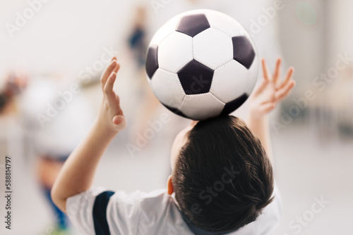 Soccer freestyle training class for school kids. Young boy keeping a soccer ball on his forehead. Youth footballer practicing soccer freestyle