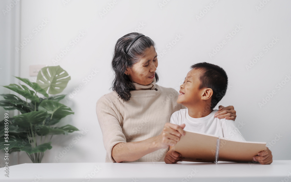 Asian grandson and grandmother people sitting together at desk doing homework at home. Asian grandson and grandmother people sitting together at desk doing homework at home.