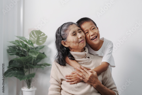Hugging, love, valentine, Asian grandson and grandmother people sitting together at desk.