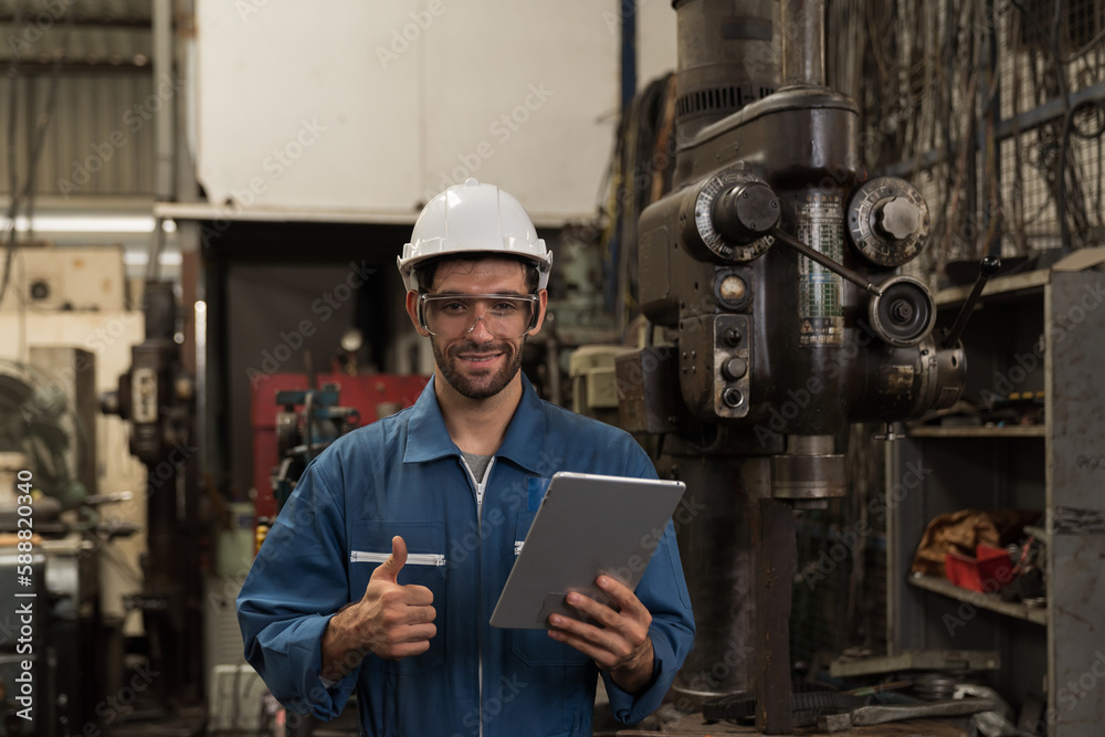 Male factory worker maintenance machine in industrial factory, working with digital tablet computer. Male technician inspecting lathe machine. Male engineer repairing machine in workshop Male factory worker maintenance machine in industrial factory, working with digital tablet computer. Male technician inspecting lathe machine. Male engineer repairing machine in workshop