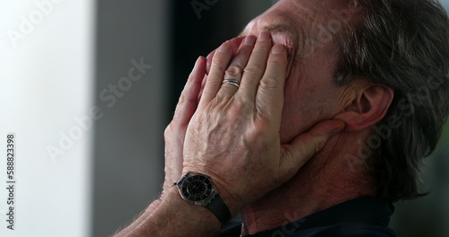 Older man rubbing face with hand