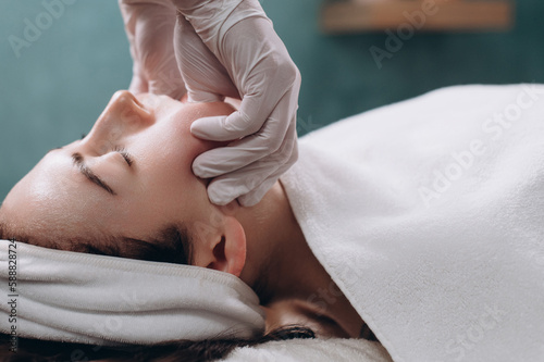 Cosmetologist makes a buccal massage of the patient's facial muscles in spa. Close up.