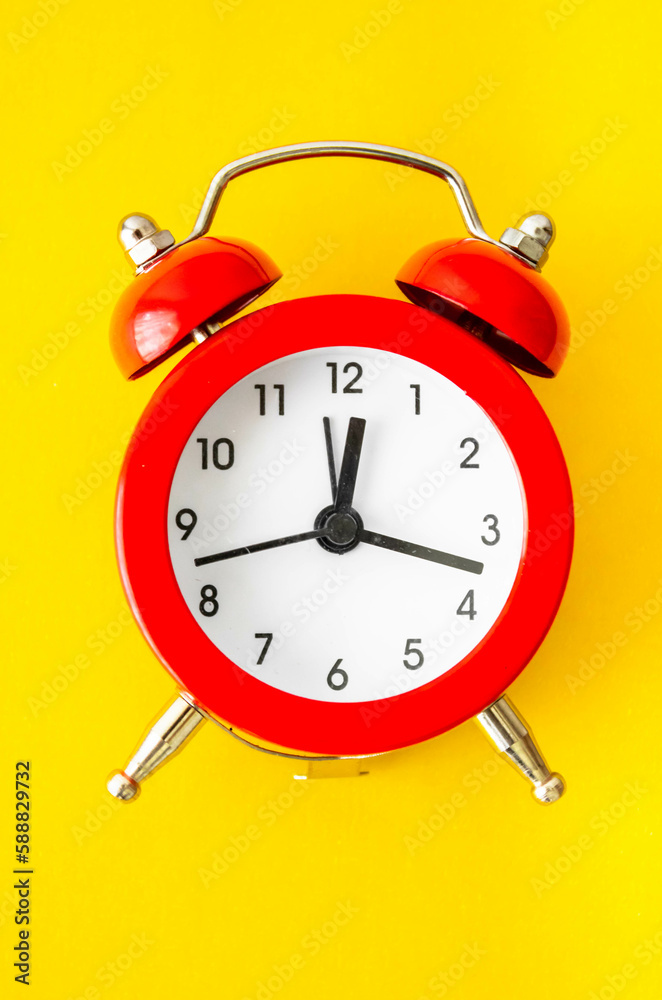 Red clock on a yellow background with natural light. Mention the schedule for personal care, physical exercise and time for medical support remedies for rheumatism, arthrosis and labyrinthitis. Red clock on a yellow background with natural light. Mention the schedule for personal care, physical exercise and time for medical support remedies for rheumatism, arthrosis and labyrinthitis.