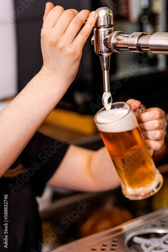 close-up of barman hand at beer tap pouring a draught lager beer