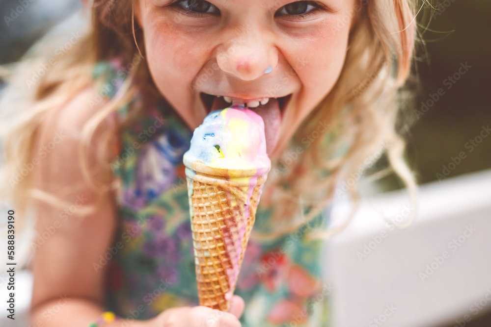Happy preschool girl eating colorful ice cream in waffle cone on sunny summer day. Little toddler child eat icecream dessert. Sweet food on hot warm summertime days. Bright light, colorful ice-cream