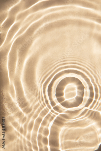 Abstract nature textured background, water waves in the pool with sun reflection. Clear water with bubbles and circles on beige background