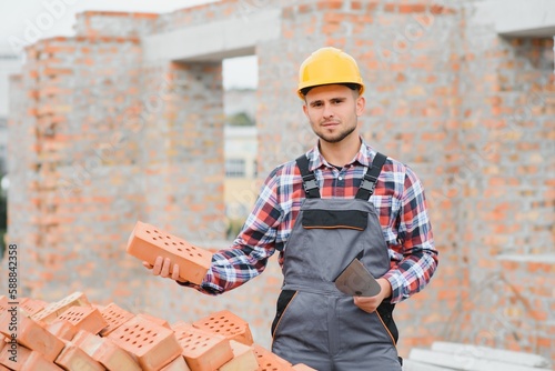 Obraz na plátně construction mason worker bricklayer installing red brick with trowel putty knife outdoors