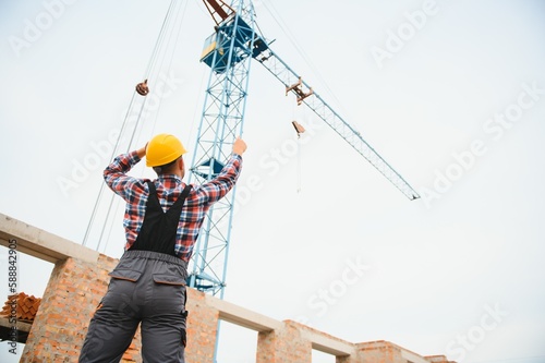 Yellow colored hard hat. Young man working in uniform at construction at daytime.
