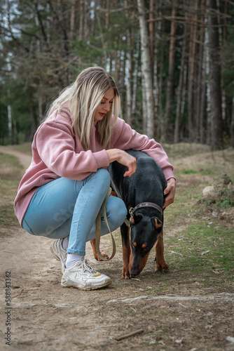 Young beautiful girl with a doberman dog in a spring park.