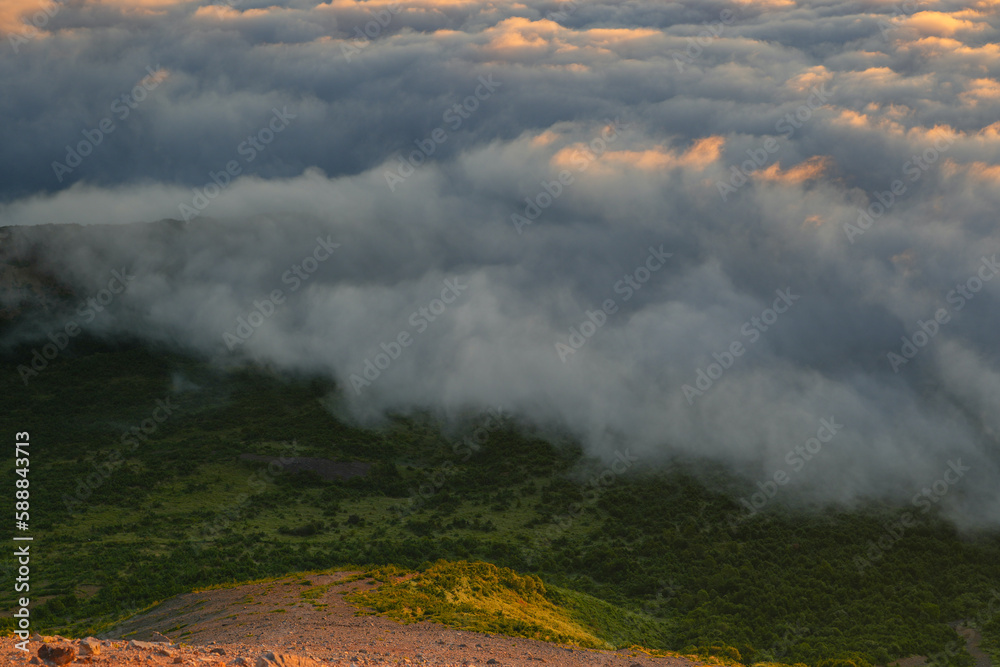 mist drifting clouds in a mountainous area, fog is over the top of a hill beside trees,