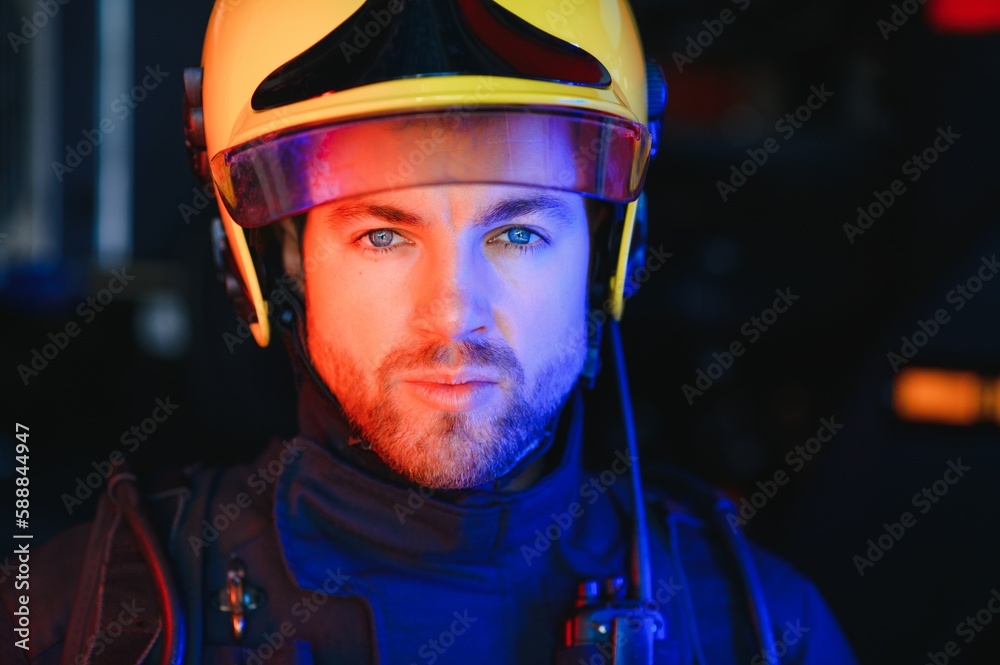 Fireman (firefighter) in action standing near a firetruck. Emergency safety. Protection, rescue from danger. Fireman (firefighter) in action standing near a firetruck. Emergency safety. Protection, rescue from danger.