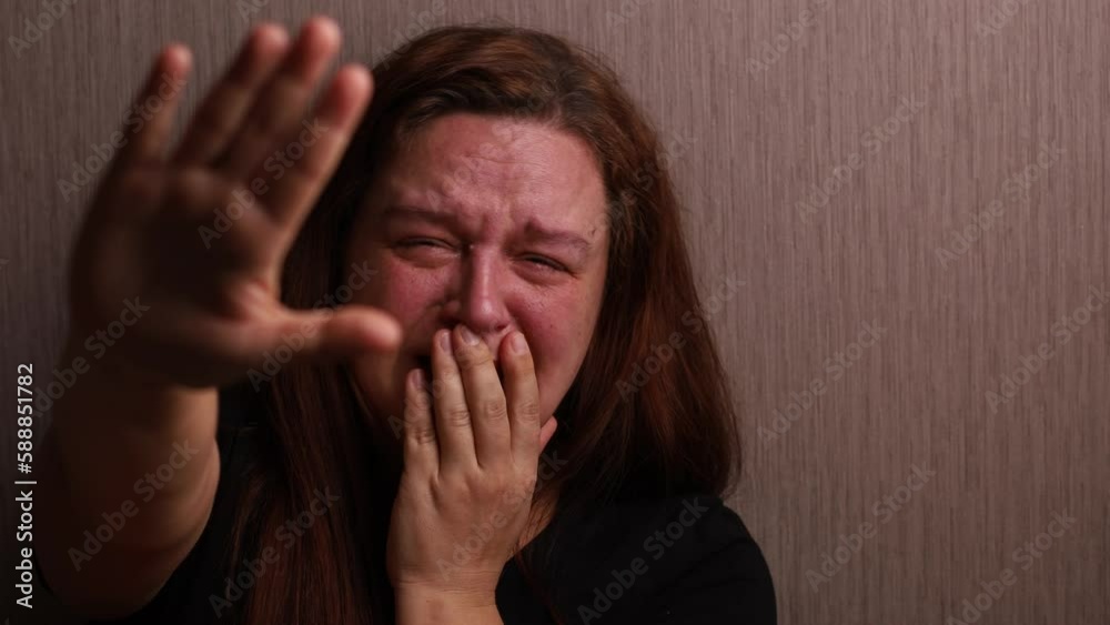 Suffering woman hysterically cry putting hand forward near room wall. Tears rolling down cheeks