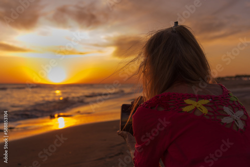 Woman holding mobile phone while taking photos of the sunset at the beach. Summer, vacation and technology concept.