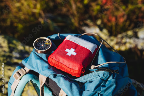 Compass first aid kit are in a backpack, a navigator in the taiga, a first aid kit in emergency situations, a white cross, medicines in a red bag. photo