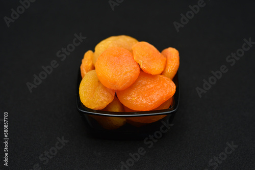 Dried peaches. Delicious dried apricots in glass bowls on a black background. photo